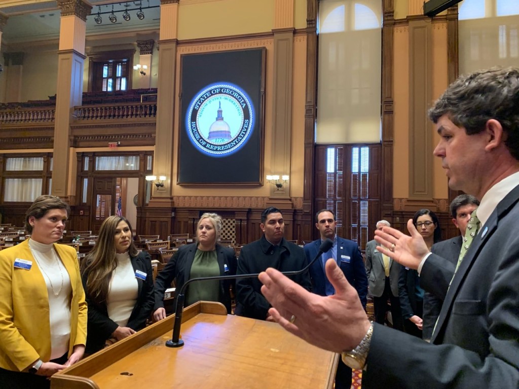 A group of people standing around a table

Description automatically generated