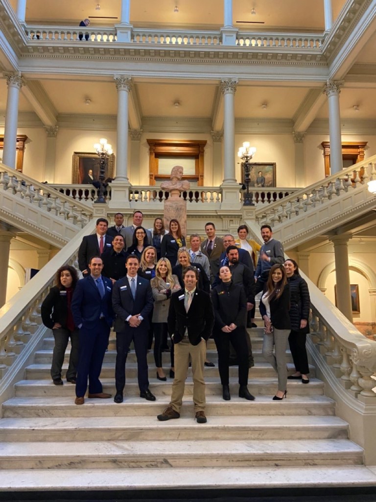 A group of people standing in front of a building

Description automatically generated